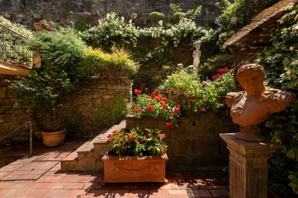 A sunlit Tuscan garden courtyard with terracotta pots and roses